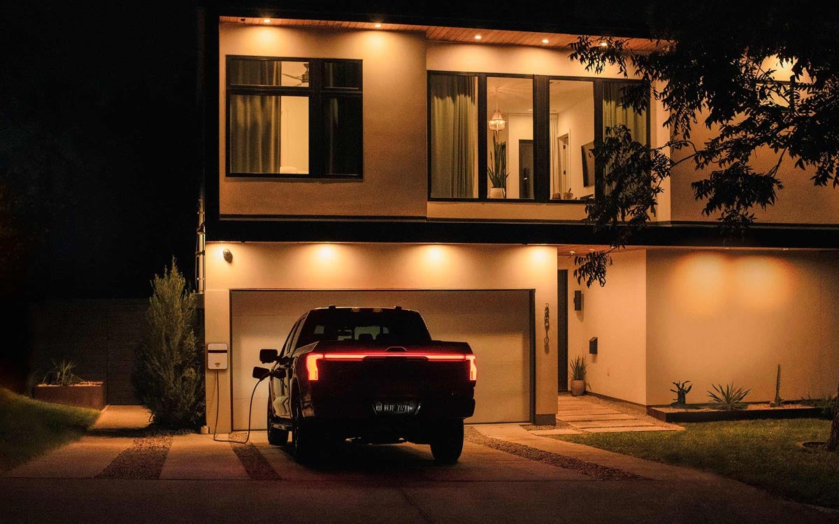 An F-150 Lightning charges in a driveway at night